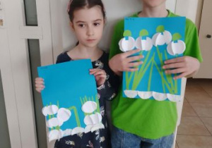 Dziewczynka z chłopcem prezentują swoje prace plastyczne przedstawiające przebiśniegi