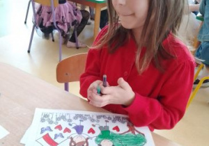 Dziewczynka koloruje ilustrację pt. "Jestem Polką i Polakiem"