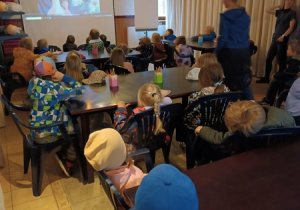 Dzieci oglądają bajkę o dinozaurach w sali 3D.