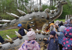 Dzieci oglądają modele dinozaurów w naturalnej wielkości.