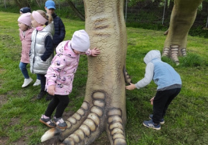 Dzieci stoją przy dinozaurze.