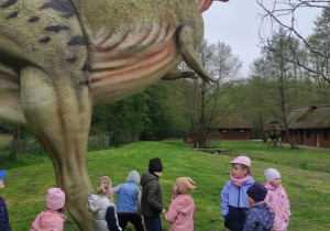 Dzieci oglądają modele dinozaurów w naturalnej wielkości.