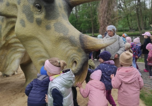 Dzieci podziwiają model dinozaura.