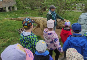 Przewodnik opowiada dzieciom o życiu i wyglądzie dinozaurów.