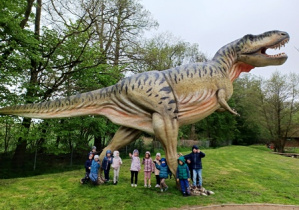 Dzieci pozują do zdjęcia z figurą Tyranozaura