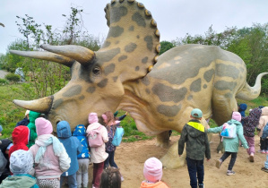 dzieci stojące obok jednej z figurek dinozaura