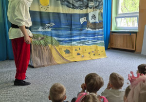 Dzieci siedzą na widowni i oglądają teatrzyk, na scenie aktor w przebraniu pirata