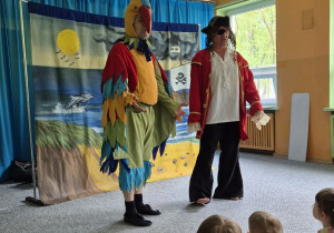 Dzieci siedzą na widowni i oglądają teatrzyk, na scenie aktor w przebraniu pirata oraz aktor w przebraniu papugi