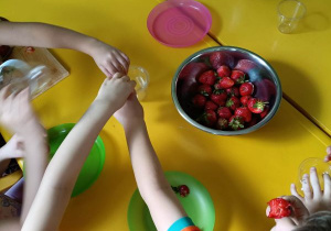 Dzieci wkładają truskawki do kubeczka