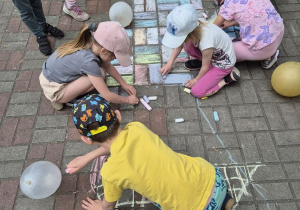 Dzieci rysują rysunki kredami w ogrodzie
