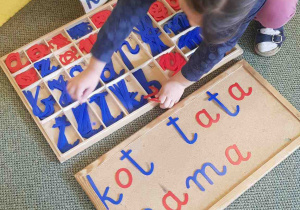 Dziewczynka układa wyrazy z liter alfabetu ruchomego