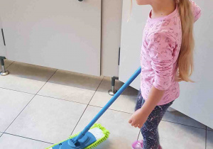 Dziewczynka samodzielnie myje podłogę mopem