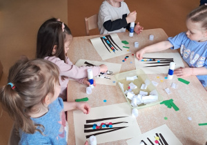 Dzieci wyklejają kolorowymi kółkami palemki