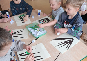 Najmłodsze dzieci wyklejają kolorowymi kółkami palemki