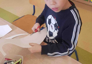 Chłopiec wycina ślimaka z papieru