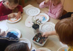 Dzieci kolorują swoje talerzyki, tworząc ozdobne muszle ślimaka
