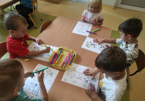 Dzieci ozdabiają kontury ubrań kolorowymi kropkami.