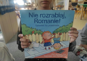 Dziewczynka prezentuje książkę z instruktażem, w jaki sposób radzić sobie w trudnych sytuacjach.