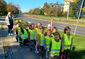 Dzieci ubrane w kamizelki odblaskowe stoją w parach