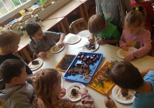 Dzieci tworzą jesienne kompozycje z kasztanó, wrzosów, pestek, ziaren kawy