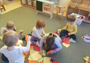 Dzieci na dywanie tworzą jesienne wianki