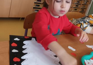 Dziewczyna wykonuje prace plastyczną z wykorzystaniem barw narodowych