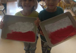 Chłopcy prezentują efekty zabawy sensorycznej z wykorzystaniem farb pt. "Flaga Polski"