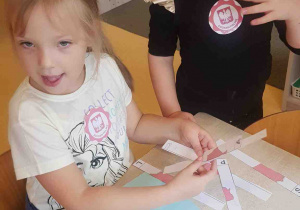 Dziewczynki wycinają paski mapy Polski i składają w całość