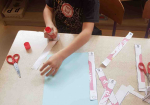 Chłopiec składa godło Polski pocięte z pasków papieru