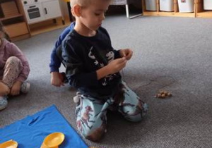 Chłopiec nawleka koralik symbolizujący dany miesiąc w pomocy edukacyjnej