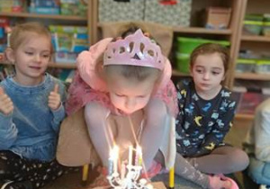 Hania zdmuchuje świeczki z urodzinowego tortu