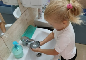 Dziewczynka myje metalowe miseczki