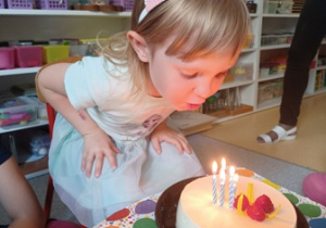 Helenka zdmuchuje 5 świeczek na torcie urodzinowym