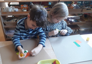 dzieci przyklejają figury geometryczne tworząc abstrakcję