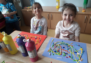 dzieci prezentują prace nakrapiane różnymi kolorami tempery