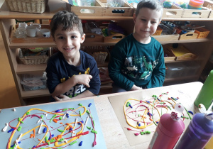 dzieci prezentują prace nakrapiane różnymi kolorami tempery