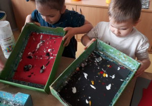 dzieci poruszają pudełkiem ze szklanymi kulkami umoczonymi w farbie