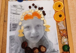 Praca plastyczna wykonana przez dziecko, polegająca na ozdobieniu swojego zdjęcia za pomocą owoców, warzyw i innego materiału przyrodniczego
