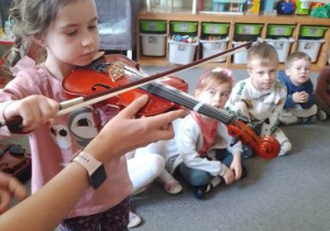 Dziewczynka podejmuje próby gry na skrzypcach