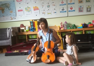 Nina z mamą w czasie warsztatów muzycznych prezentują instrumenty - skrzypce oraz altówkę
