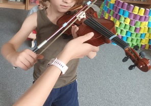Chłopiec trzyma w dłoniach skrzypce